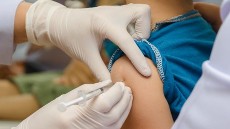 doctor gives injection of vaccine to boys arm
